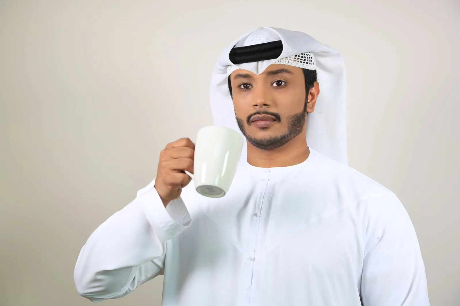 Young man in traditional attire with a coffee